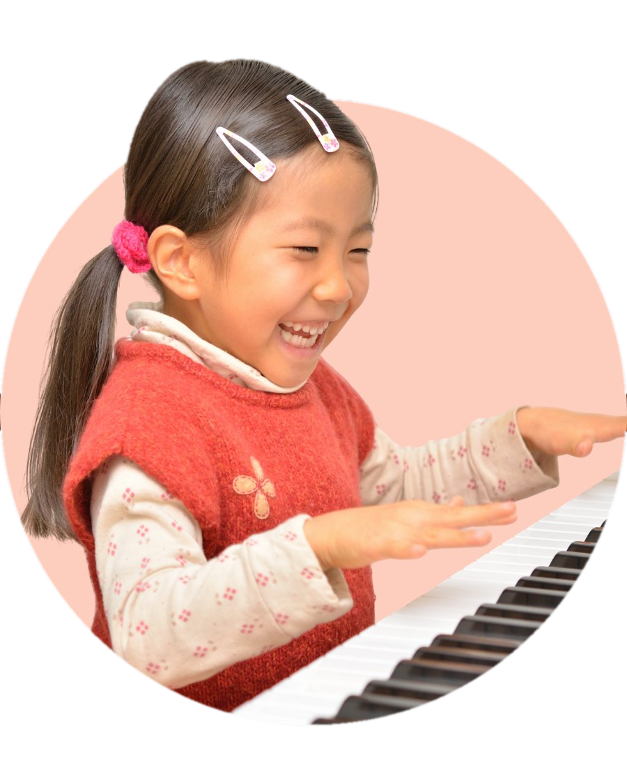 A young girl laughing with delight while playing piano during an in-home lesson